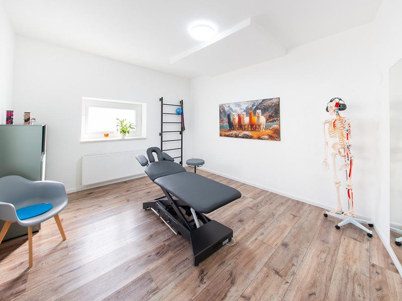 Behandlungsraum mit Therapieliege, Sprossenwand und Skelettmodell