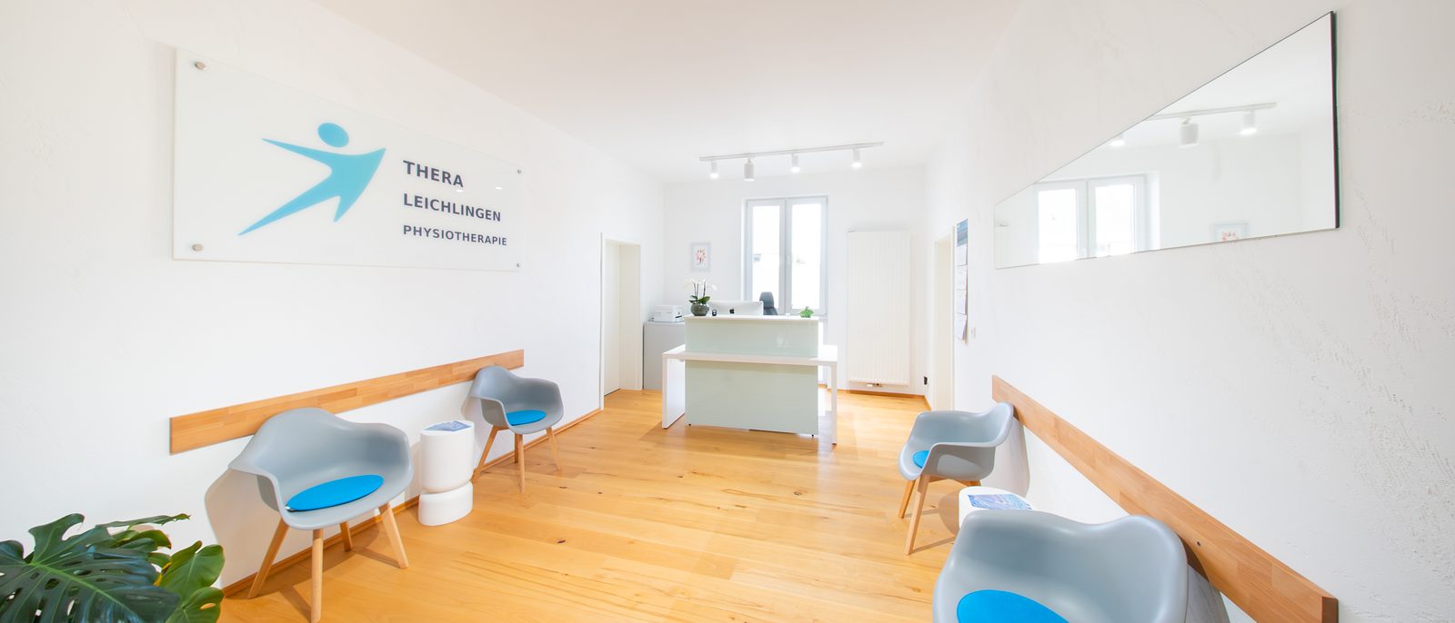 Empfang und Wartebereich von THERA Leichlingen mit dem Praxislogo an der Wand